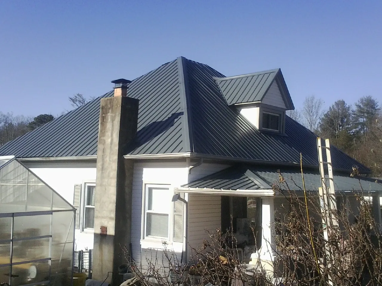 Dark blue standing seam metal roof on a white farmhouse with dormer — Slate & Tile Roof Repair by Roofing Brothers in Belgium