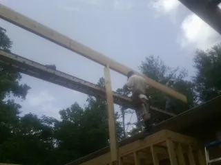 Carpenter setting a ridge beam over a new addition frame — Ice Dam Removal by Roofing Brothers in Belgium