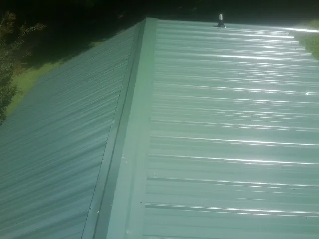New green metal panels meeting at the ridge of a roof — Flat Roof Repair work by our crew in Belgium