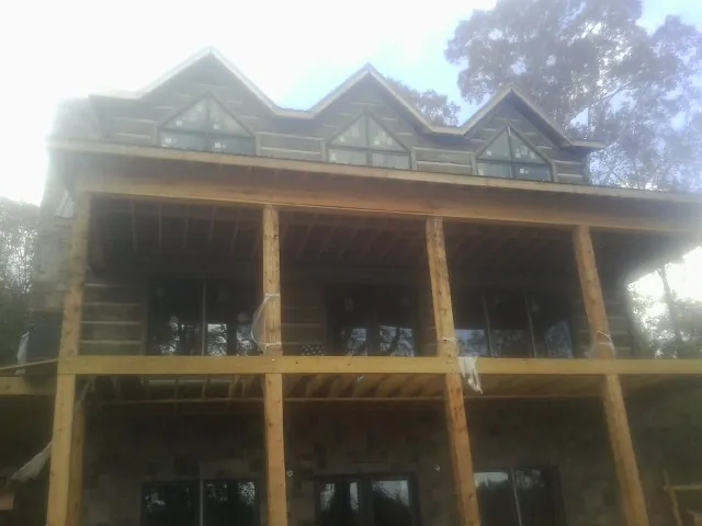 Dormers and porch framing on a large log home under construction — Roof Coating work by our crew in Belgium