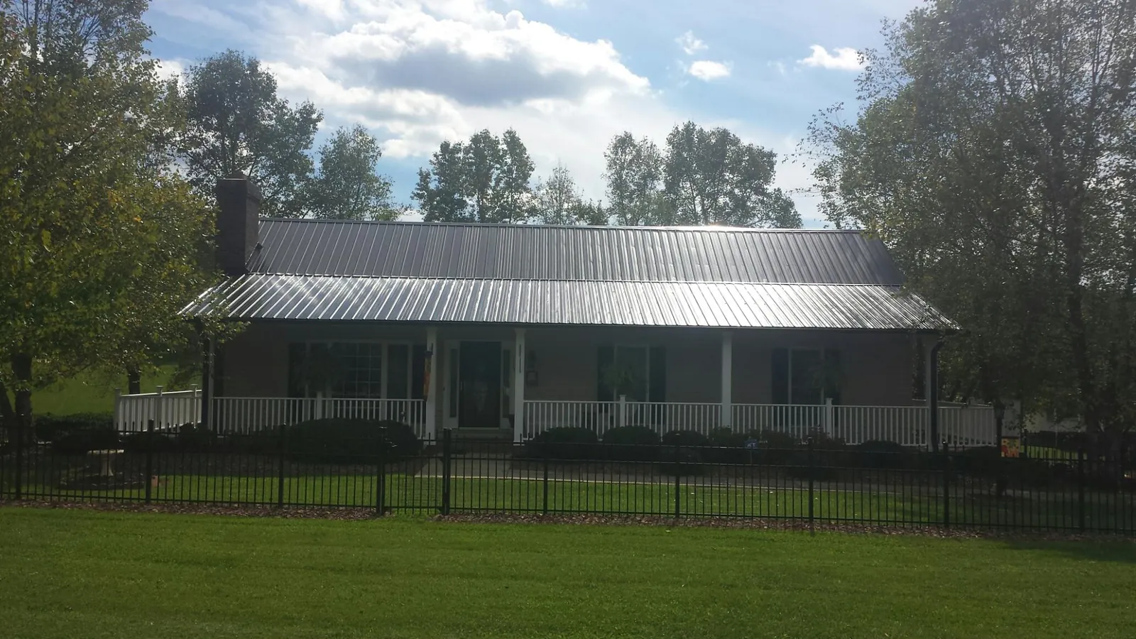Gray metal roof on a brick ranch with a full width front porch — Gutter Guard Installation work by our crew in Belgium