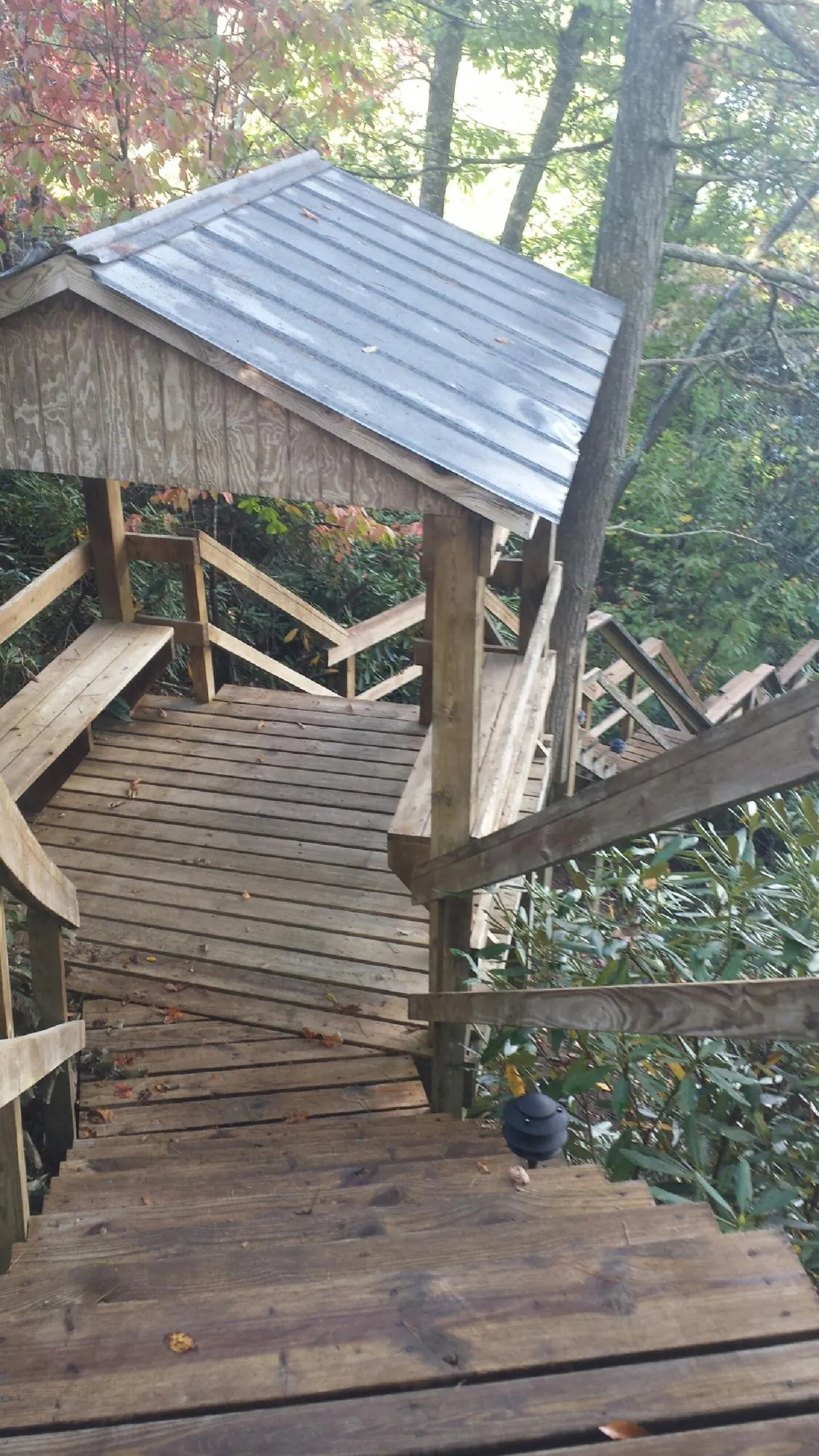Metal roofed shelter over wooden steps on a wooded walkway — Skylight Repair & Installation work by our crew in Belgium