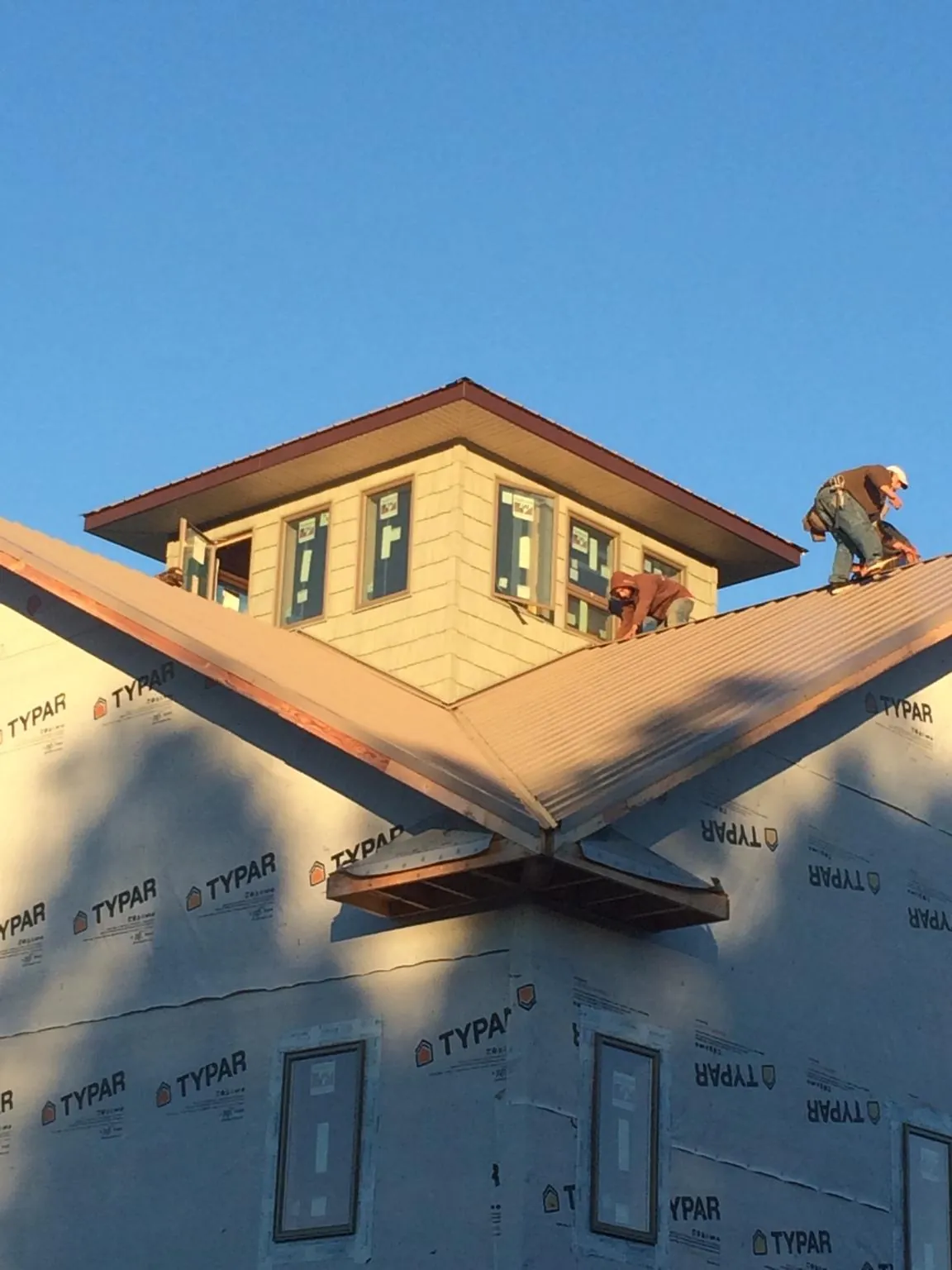 Roofers working around a rooftop cupola on a new metal roof at sunset — Roof Waterproofing in Belgium by Roofing Brothers